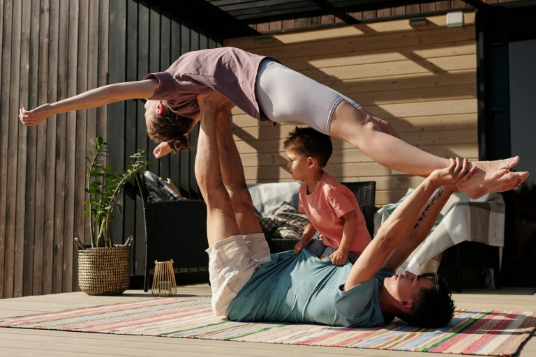 Father and kids doing yoga outdoors on a patio, balancing poses together.